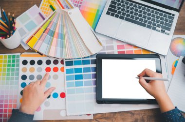 Graphic designer architects who work with laptops and color comparison tables for design work.	