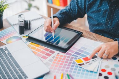 Graphic designer architects who work with laptops and color comparison tables for design work.	