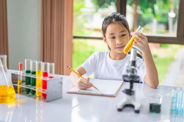 小科学家通过显微镜和充满化学物质的试管来学习科学和实验 — 图库照片