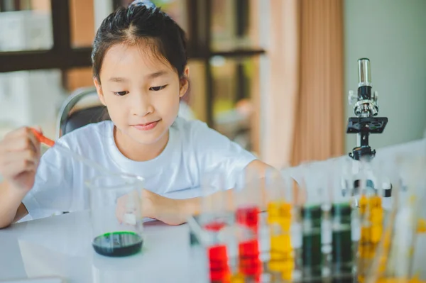 little scientist looking through a microscope and test tubes filled with chemicals for learning about science and experiments.