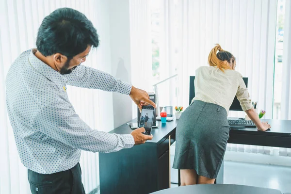 boss or supervisor is secretly using a mobile phone to film the buttocks of a female employee at work. Causing young employees to resist because they are uncomfortable and afraid of being sexually harassed There is sexual harassment in the workplace.