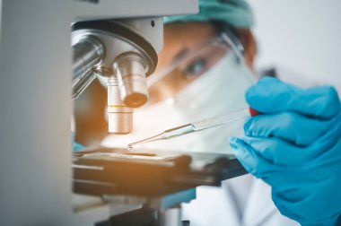 Female researchers are experimenting with pipette dropping a sample into a test tube in an experiment research in laboratory..	