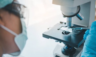 Female researchers are experimenting with pipette dropping a sample into a test tube in an experiment research in laboratory..	