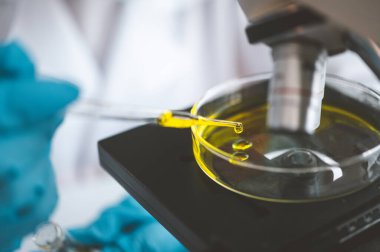 Female researchers are experimenting with pipette dropping a sample into a test tube in an experiment research in laboratory..	