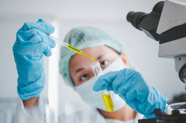 Female researchers are experimenting with pipette dropping a sample into a test tube in an experiment research in laboratory..	