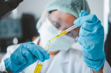 Female researchers are experimenting with pipette dropping a sample into a test tube in an experiment research in laboratory..	
