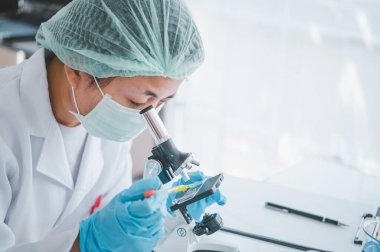 Female researchers are experimenting with pipette dropping a sample into a test tube in an experiment research in laboratory..	