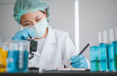 Female researchers are experimenting with pipette dropping a sample into a test tube in an experiment research in laboratory..	