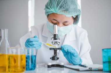 Female researchers are experimenting with pipette dropping a sample into a test tube in an experiment research in laboratory..	