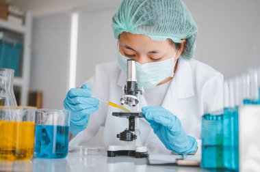 Female researchers are experimenting with pipette dropping a sample into a test tube in an experiment research in laboratory..	