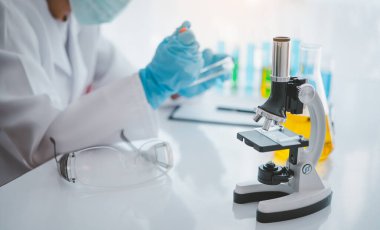 Female researchers are experimenting with pipette dropping a sample into a test tube in an experiment research in laboratory..	