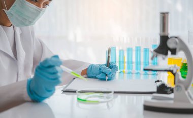 Female researchers are experimenting with pipette dropping a sample into a test tube in an experiment research in laboratory..	