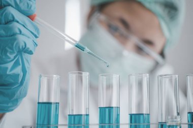 Female researchers are experimenting with pipette dropping a sample into a test tube in an experiment research in laboratory..	