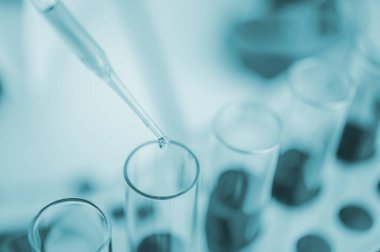 Yakın çekim pipeti laboratuardaki deney araştırmasında bir numuneyi test tüpüne atıyor.