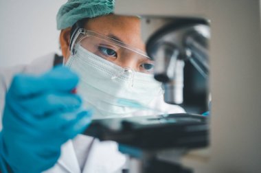 Female researchers are experimenting with pipette dropping a sample into a test tube in an experiment research in laboratory..	