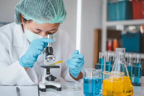 stock image Female researchers are experimenting with pipette dropping a sample into a test tube in an experiment research in laboratory..	