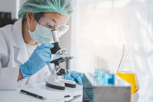 stock image female medical researcher looking at a microscope in a medical laboratory. Medical experimental concept	