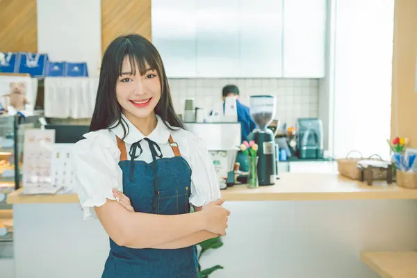 stock image female cafe owner poses in front of the counter to welcome customers who come in to place orders in the cafe.