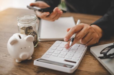 Kapatın. İş adamı hesap makinesinin üzerinde oturuyor ve mali muhasebe konseptinde grafiği var.