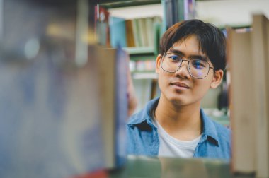 Erkek kolej öğrencileri okumak için kitap arıyorlar, kütüphanedeki kitaplıklarda raporlar hazırlıyorlar. Okul konseptine geri dönüyorlar.