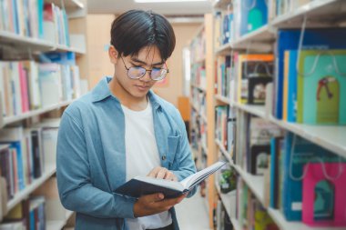 Öğrenciler okumak ve okumak için kitap arıyorlar, rapor hazırlıyorlar, kütüphanedeki kitaplıklarda yararlı bilgiler buluyorlar. Okuma, öğrenme ve zeka kavramı.