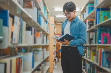 Öğrenciler okumak ve okumak için kitap arıyorlar, rapor hazırlıyorlar, kütüphanedeki kitaplıklarda yararlı bilgiler buluyorlar. Okuma, öğrenme ve zeka kavramı.