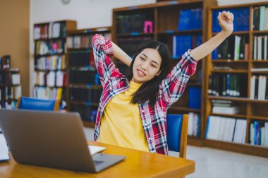 Öğrenciler laptopları üzerinde çalıştıktan sonra dinleniyorlar ve çalışmak için kitap arıyorlar, rapor hazırlıyorlar, üniversite odasında yararlı bilgiler buluyorlar..