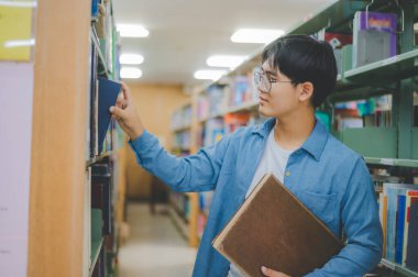 Erkek kolej öğrencileri okumak için kitap arıyorlar, kütüphanedeki kitaplıklarda raporlar hazırlıyorlar. Okul konseptine geri dönüyorlar.