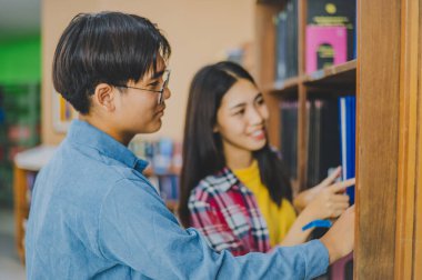 Öğrenciler birbirlerine kitap bulmada ve okumak, rapor hazırlamak, kütüphanedeki kitaplıklarda yararlı bilgiler bulmak için danışmanlık yapıyorlar. Okuma, öğrenme ve zeka kavramı.