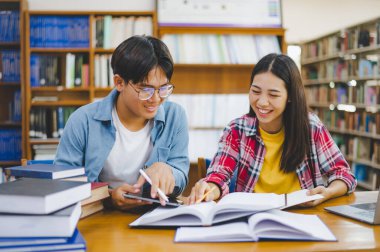Öğrenciler birbirlerine danışarak dizüstü bilgisayarlar üzerinde çalışıyor ve çalışmak için kitaplar arıyor, raporlar hazırlıyor, üniversite odasında yararlı bilgiler buluyor. Okuma, öğrenme ve zeka kavramı.