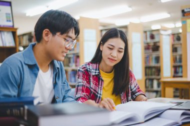 Öğrenciler birbirlerine danışarak dizüstü bilgisayarlar üzerinde çalışıyor ve çalışmak için kitaplar arıyor, raporlar hazırlıyor, üniversite odasında yararlı bilgiler buluyor. Okuma, öğrenme ve zeka kavramı.
