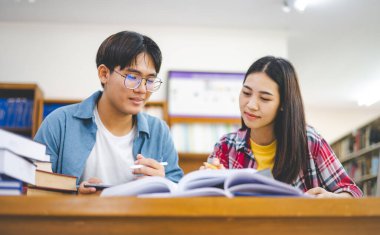 Öğrenciler birbirlerine danışarak dizüstü bilgisayarlar üzerinde çalışıyor ve çalışmak için kitaplar arıyor, raporlar hazırlıyor, üniversite odasında yararlı bilgiler buluyor. Okuma, öğrenme ve zeka kavramı.