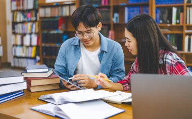 Öğrenciler birbirlerine danışarak dizüstü bilgisayarlar üzerinde çalışıyor ve çalışmak için kitaplar arıyor, raporlar hazırlıyor, üniversite odasında yararlı bilgiler buluyor. Okuma, öğrenme ve zeka kavramı.