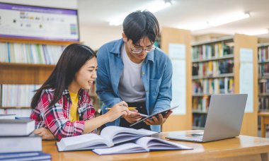 Öğrenciler birbirlerine danışarak dizüstü bilgisayarlar üzerinde çalışıyor ve çalışmak için kitaplar arıyor, raporlar hazırlıyor, üniversite odasında yararlı bilgiler buluyor. Okuma, öğrenme ve zeka kavramı.
