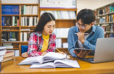 Öğrenciler birbirlerine danışarak dizüstü bilgisayarlar üzerinde çalışıyor ve çalışmak için kitaplar arıyor, raporlar hazırlıyor, üniversite odasında yararlı bilgiler buluyor. Okuma, öğrenme ve zeka kavramı.