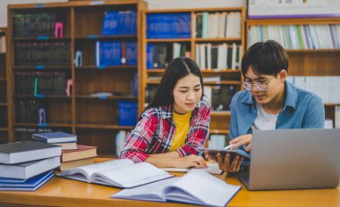 Öğrenciler birbirlerine danışarak dizüstü bilgisayarlar üzerinde çalışıyor ve çalışmak için kitaplar arıyor, raporlar hazırlıyor, üniversite odasında yararlı bilgiler buluyor. Okuma, öğrenme ve zeka kavramı.