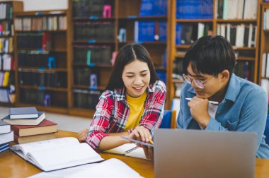 Öğrenciler birbirlerine danışarak dizüstü bilgisayarlar üzerinde çalışıyor ve çalışmak için kitaplar arıyor, raporlar hazırlıyor, üniversite odasında yararlı bilgiler buluyor. Okuma, öğrenme ve zeka kavramı.