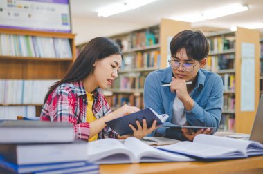 Öğrenciler birbirlerine danışarak dizüstü bilgisayarlar üzerinde çalışıyor ve çalışmak için kitaplar arıyor, raporlar hazırlıyor, üniversite odasında yararlı bilgiler buluyor. Okuma, öğrenme ve zeka kavramı.