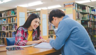 Öğrenciler birbirlerine danışarak dizüstü bilgisayarlar üzerinde çalışıyor ve çalışmak için kitaplar arıyor, raporlar hazırlıyor, üniversite odasında yararlı bilgiler buluyor. Okuma, öğrenme ve zeka kavramı.