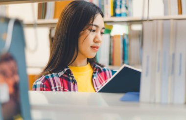 Öğrenciler okumak ve okumak için kitap arıyorlar, rapor hazırlıyorlar, kütüphanedeki kitaplıklarda yararlı bilgiler buluyorlar. Okuma, öğrenme ve zeka kavramı.