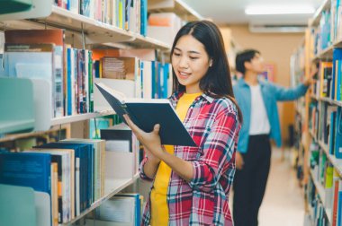 Öğrenciler okumak ve okumak için kitap arıyorlar, rapor hazırlıyorlar, kütüphanedeki kitaplıklarda yararlı bilgiler buluyorlar. Okuma, öğrenme ve zeka kavramı.