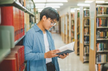 Öğrenciler okumak ve okumak için kitap arıyorlar, rapor hazırlıyorlar, kütüphanedeki kitaplıklarda yararlı bilgiler buluyorlar. Okuma, öğrenme ve zeka kavramı.