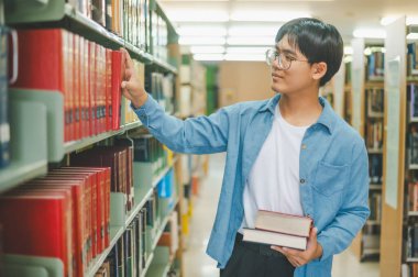 Erkek kolej öğrencileri okumak için kitap arıyorlar, kütüphanedeki kitaplıklarda raporlar hazırlıyorlar. Okul konseptine geri dönüyorlar.