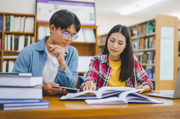 Öğrenciler birbirlerine danışarak dizüstü bilgisayarlar üzerinde çalışıyor ve çalışmak için kitaplar arıyor, raporlar hazırlıyor, üniversite odasında yararlı bilgiler buluyor. Okuma, öğrenme ve zeka kavramı.