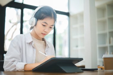 Kulaklık takan Asyalı ergen öğrenciler çevrimiçi öğrenim için video konferansı aracılığıyla iletişim kuruyorlar. Bir videoda, kulaklık takan Asyalı gençler çevrimiçi öğrenim için video konferansı aracılığıyla iletişim kuruyorlar. Bir video konferansında