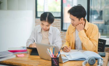 Ödev yapan genç üniversite öğrencileri, işbirliği yapan araştırma planı kavramları ve stratejileri tartışıyor. Dizüstü bilgisayarlarda ve tablet bilgisayarlarda sunumları hazırlayın.