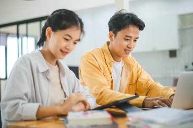 Ödev yapan genç üniversite öğrencileri, işbirliği yapan araştırma planı kavramları ve stratejileri tartışıyor. Dizüstü bilgisayarlarda ve tablet bilgisayarlarda sunumları hazırlayın.