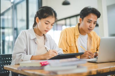 Ödev yapan genç üniversite öğrencileri, işbirliği yapan araştırma planı kavramları ve stratejileri tartışıyor. Dizüstü bilgisayarlarda ve tablet bilgisayarlarda sunumları hazırlayın.