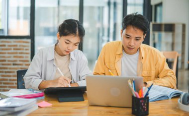 Ödev yapan genç üniversite öğrencileri, işbirliği yapan araştırma planı kavramları ve stratejileri tartışıyor. Dizüstü bilgisayarlarda ve tablet bilgisayarlarda sunumları hazırlayın.