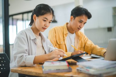 Ödev yapan genç üniversite öğrencileri, işbirliği yapan araştırma planı kavramları ve stratejileri tartışıyor. Dizüstü bilgisayarlarda ve tablet bilgisayarlarda sunumları hazırlayın.
